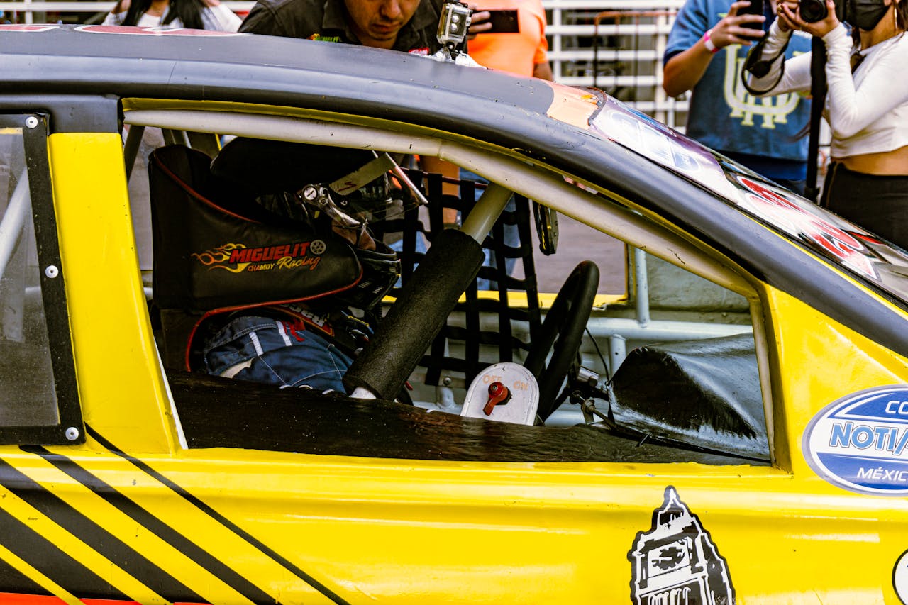 A man in a yellow car with a helmet on