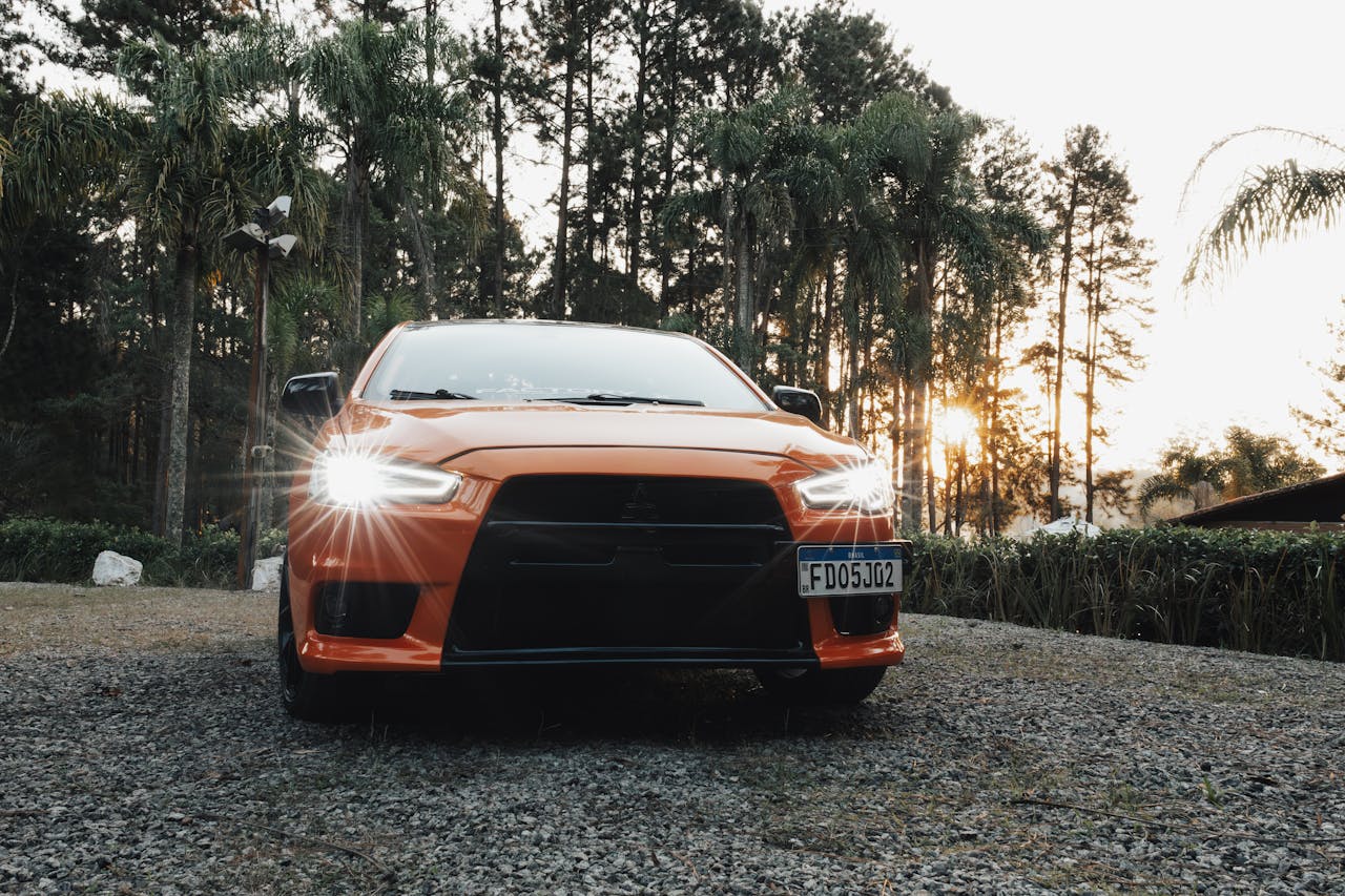 An orange car parked in front of a forest